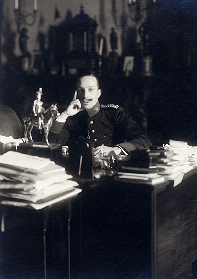 Retrato del rey Alfonso XIII sentado ante su mesa de despacho con el uniforme del regimiento Inmemorial del rey